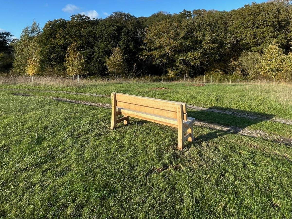 Wooden bench in field adjacent to track