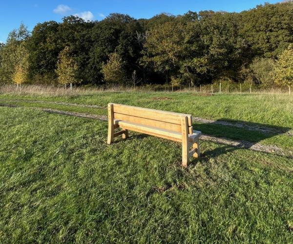 Wooden bench in field adjacent to track